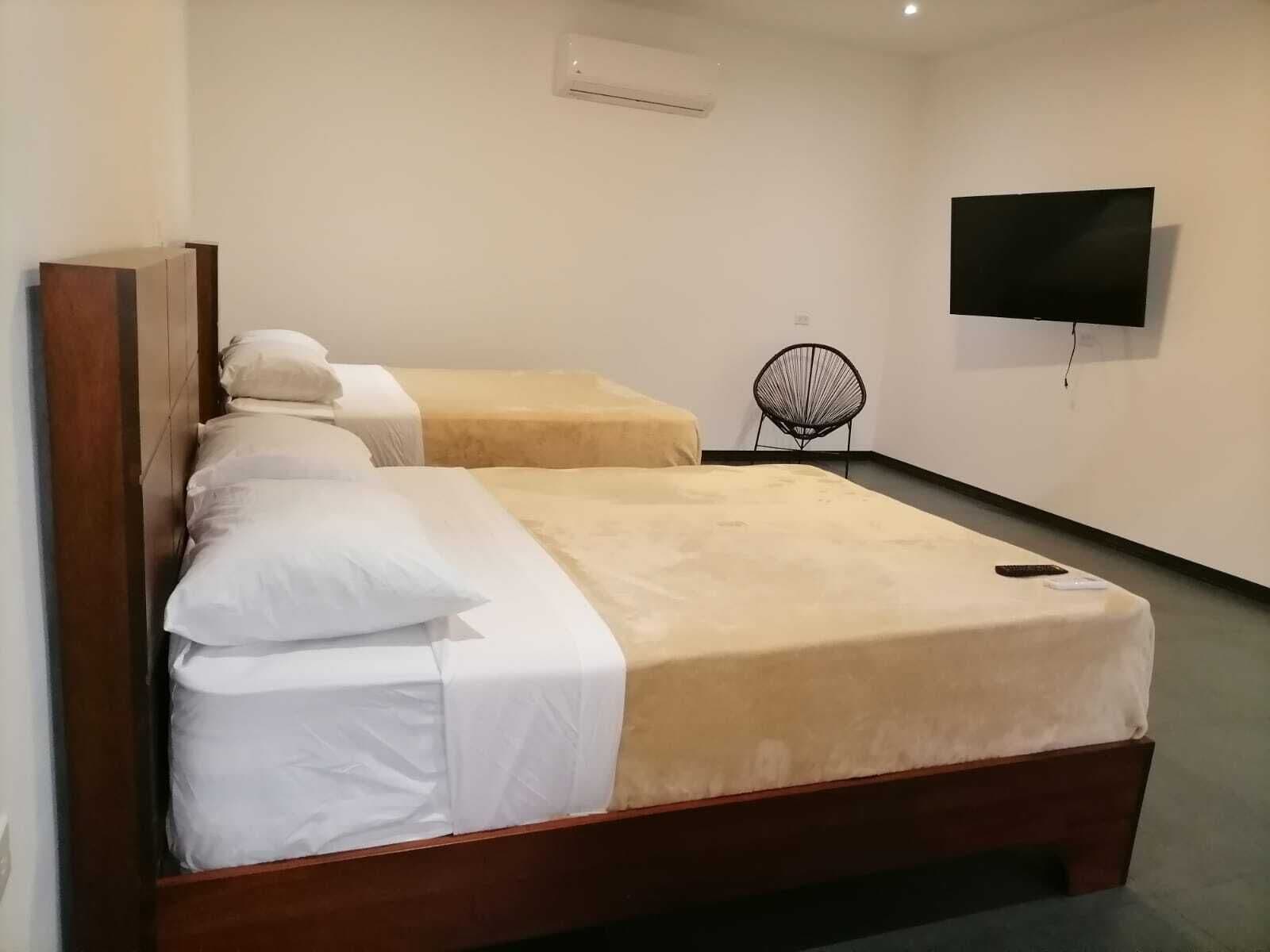 Une chambre d’hôtel avec deux lits, un téléviseur fixé au mur et une chaise.