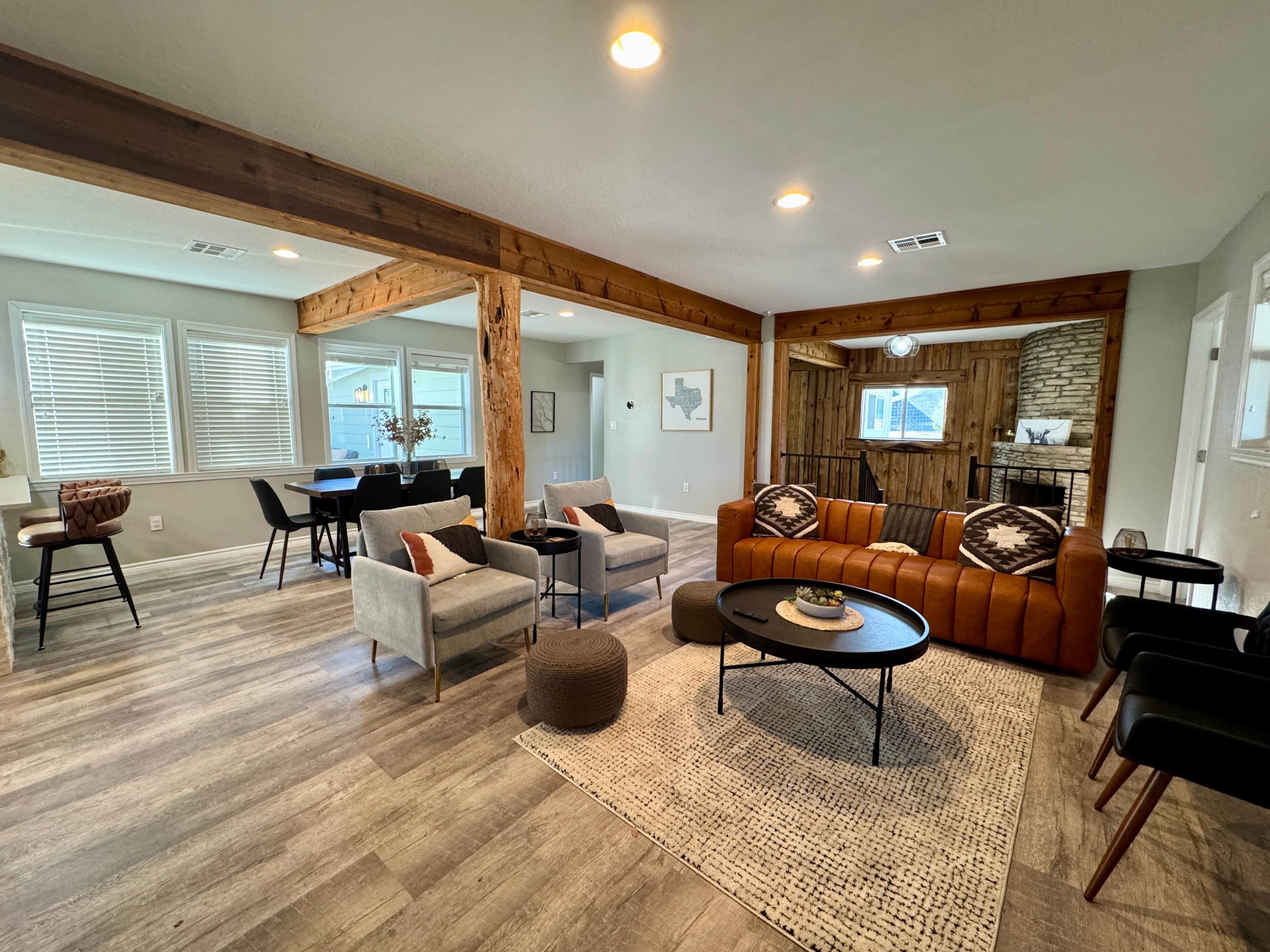 A spacious living area with a wooden ceiling, a stone fireplace, and a dining area with a view.