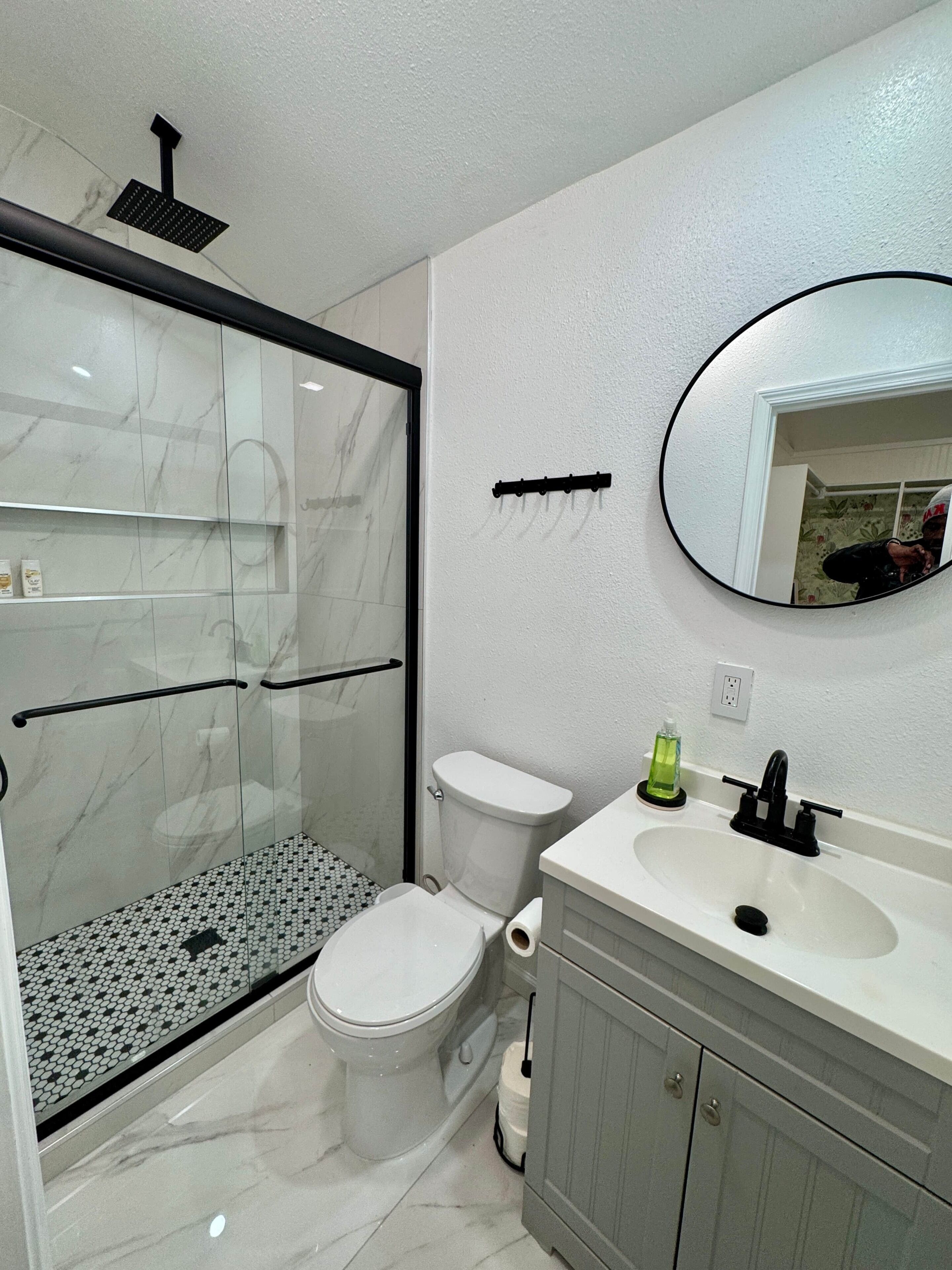 A bathroom with a glass-enclosed shower, a toilet, a sink, and a mirror.
