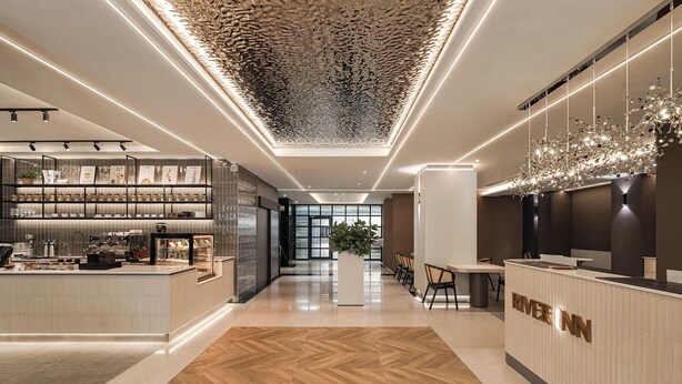 A modern hotel lobby with a reception desk, a coffee bar, and a seating area. - River inn ZihLi (Kaohsiung)