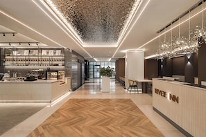A modern hotel lobby with a reception desk, a coffee bar, and a seating area. - River inn ZihLi (Kaohsiung)