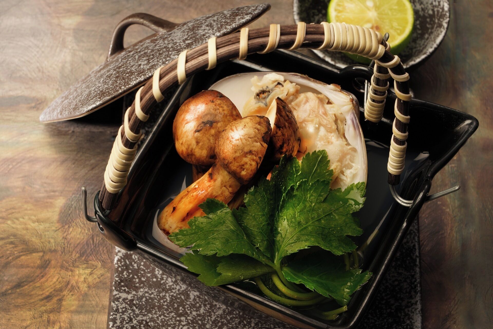 Un repas servi dans un plateau noir avec un couvercle, comprenant du poulet grillé, du riz et un quartier de citron vert.