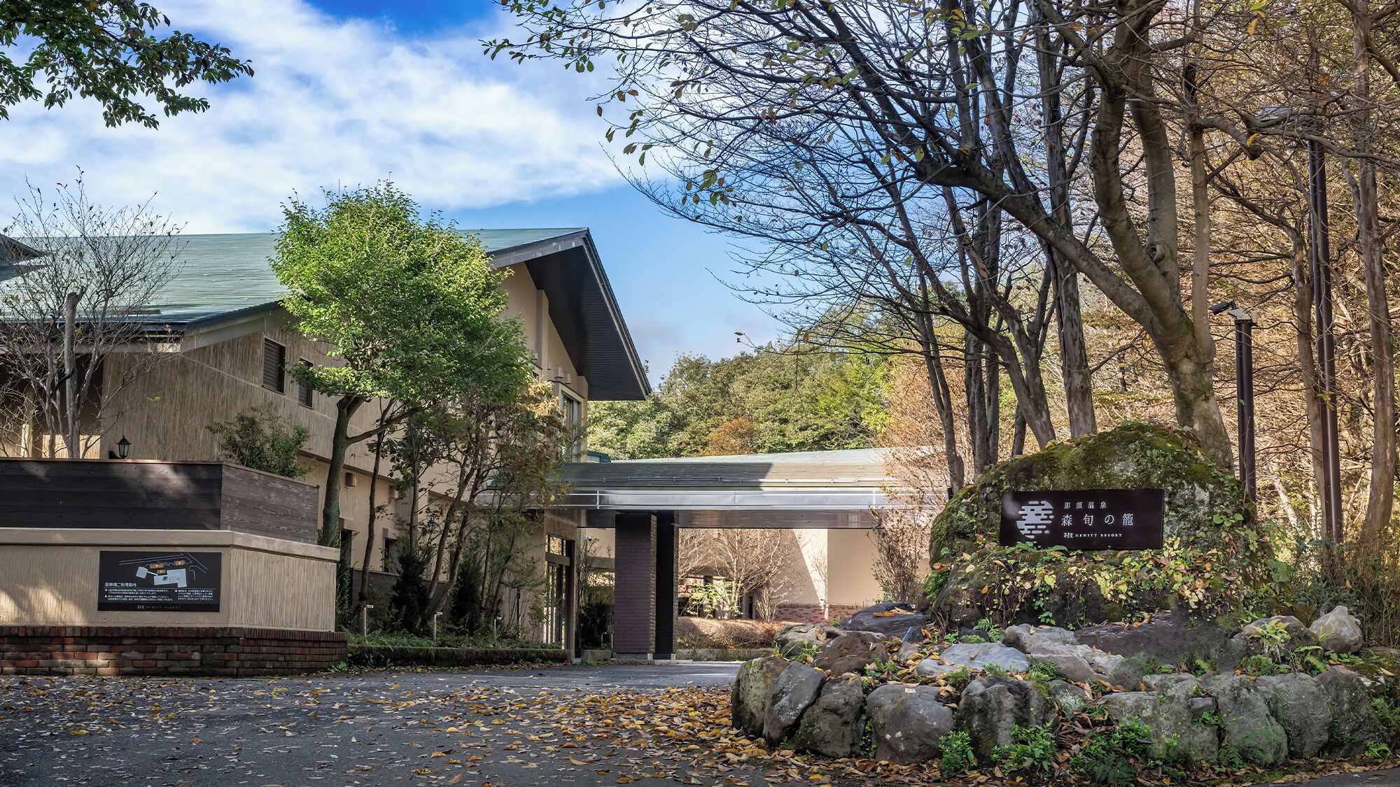 A building with a covered entrance, surrounded by trees and rocks.