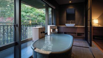 A modern bathroom with a freestanding hot tub, a sink, and a mirror.