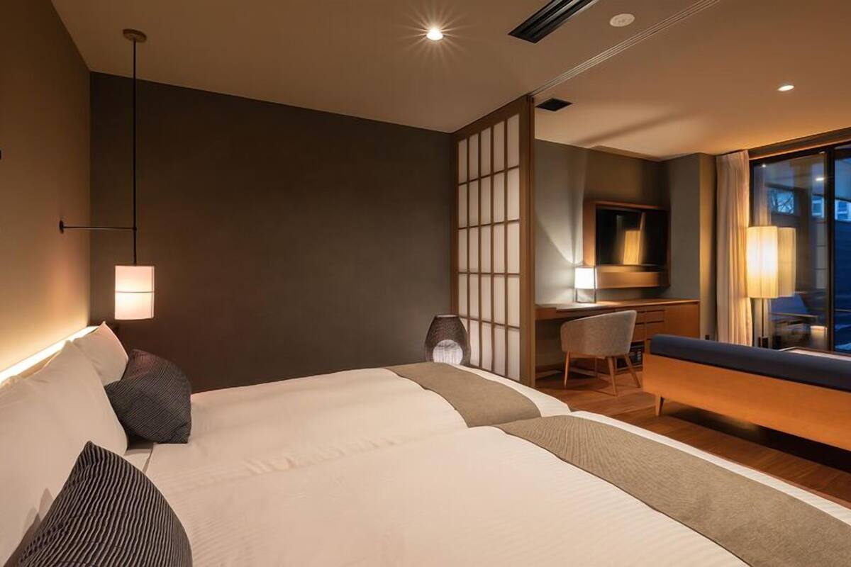 Habitación de hotel con una cama grande, un escritorio, una silla y vistas al exterior.