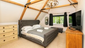 A bedroom with a bed, dresser, TV, and a window with curtains. - Lodge Farm - Stunning 3 BD with Garden (Oxford)