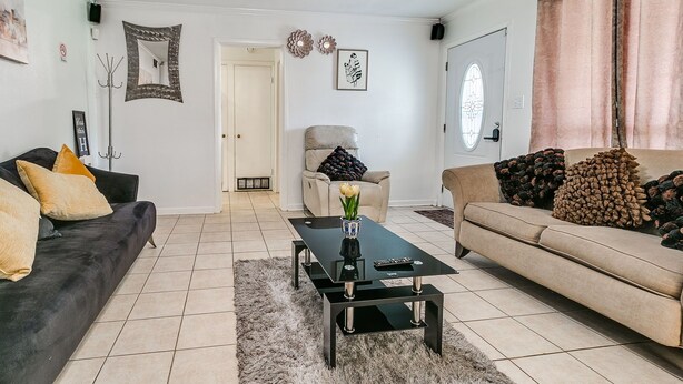 A living room with a black coffee table, two sofas, a beige sofa, and a door in the background.