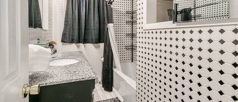 A bathroom with a white sink, a black bathtub, and a shower curtain.