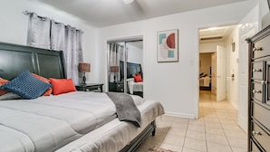 A bedroom with a bed, a dresser, a mirror, and a door leading to another room.