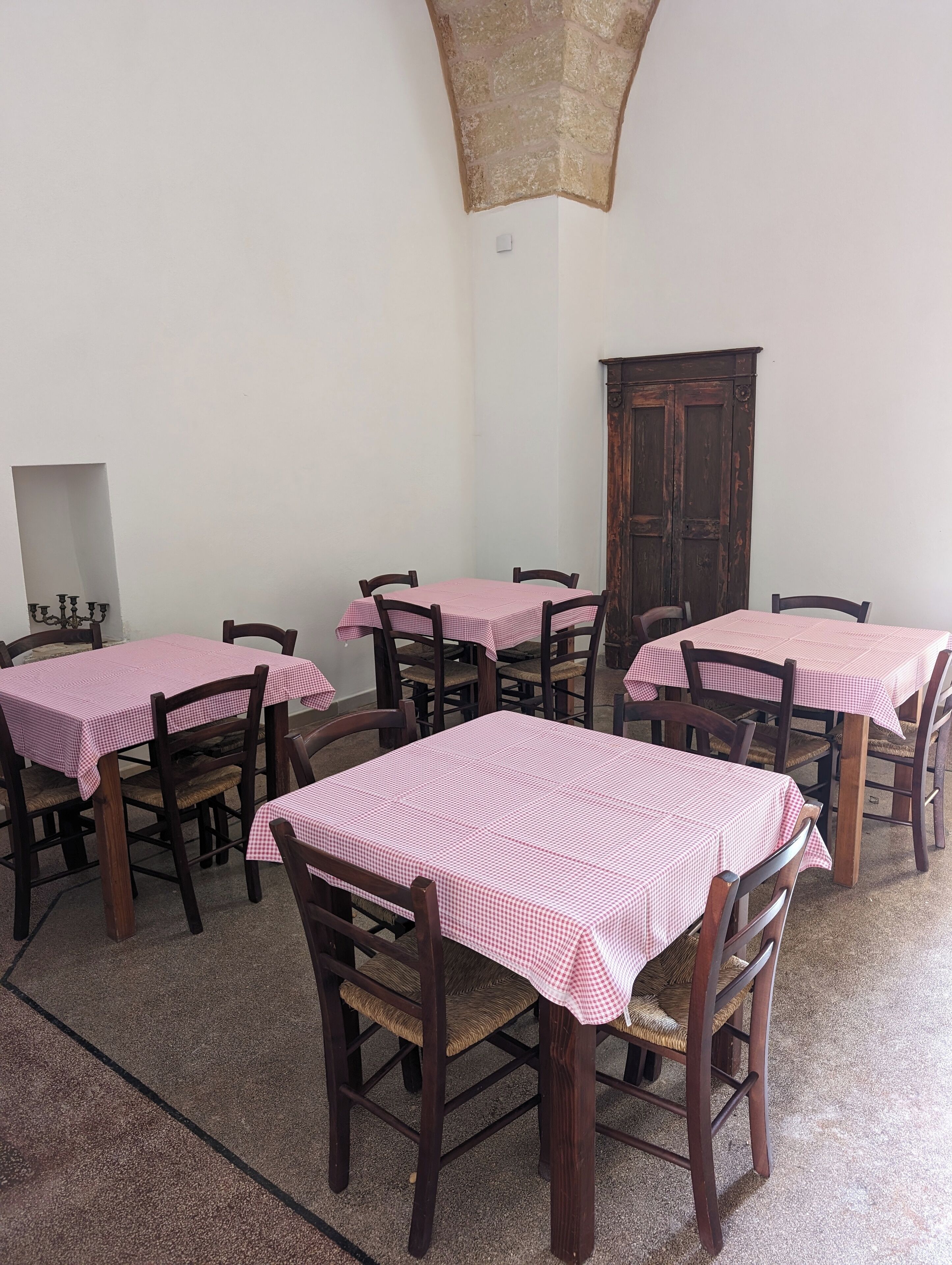A dining area with wooden tables and chairs, each covered with a checkered tablecloth.