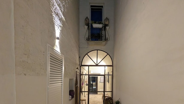 A narrow, stone-paved courtyard with a white door and a small table with chairs.