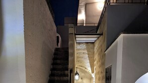 A narrow stone staircase leading to a door with a green frame, surrounded by walls with a textured finish.