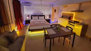 Een moderne hotelkamer met een bed, een eettafel en een kitchenette.