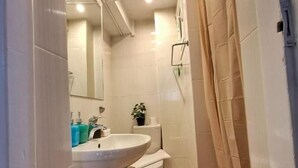 Een kleine badkamer met een wastafel, toilet en douchehoek.