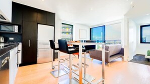 A modern kitchen with a dining area, a refrigerator, and a view of the city.