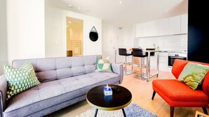 A modern living room with a grey sofa, a red armchair, and a round coffee table.