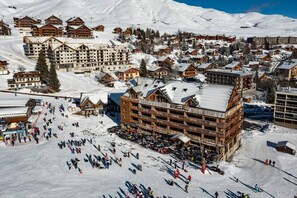Une station de ski comprenant plusieurs chalets en bois, un télésiège et un grand bâtiment doté de balcons.