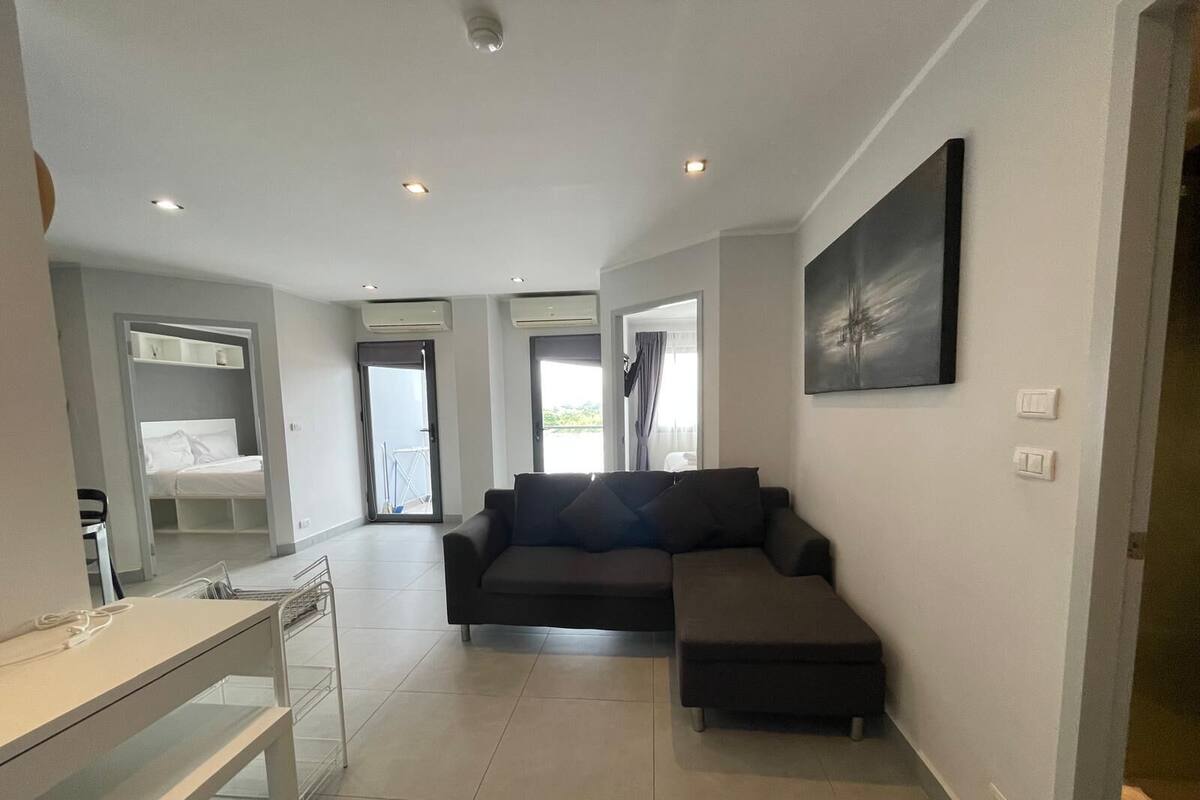 A modern living room with a sofa, a small table, and a bed in the corner.