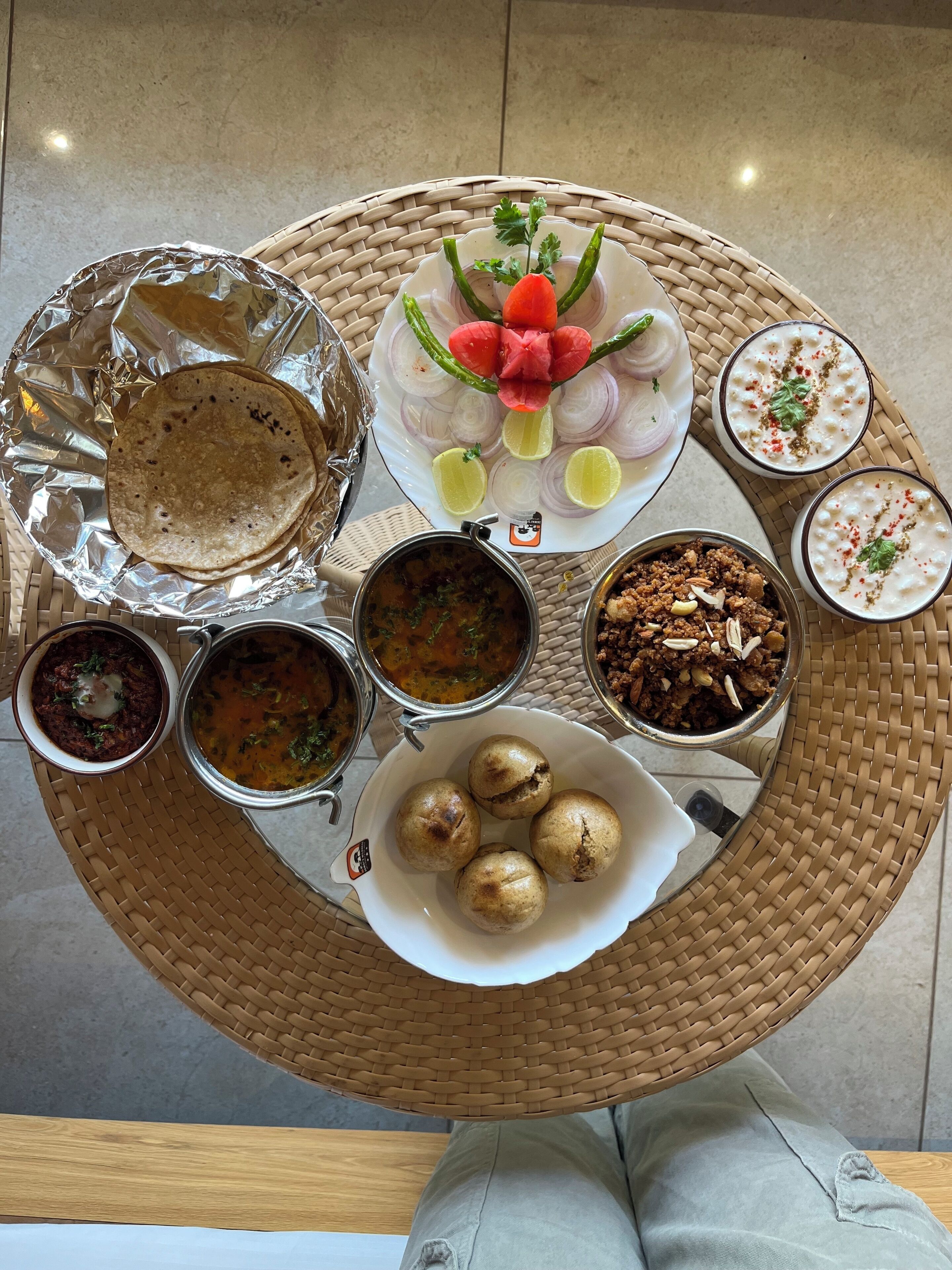 A round table with various dishes including flatbreads, a salad, and several bowls of food.