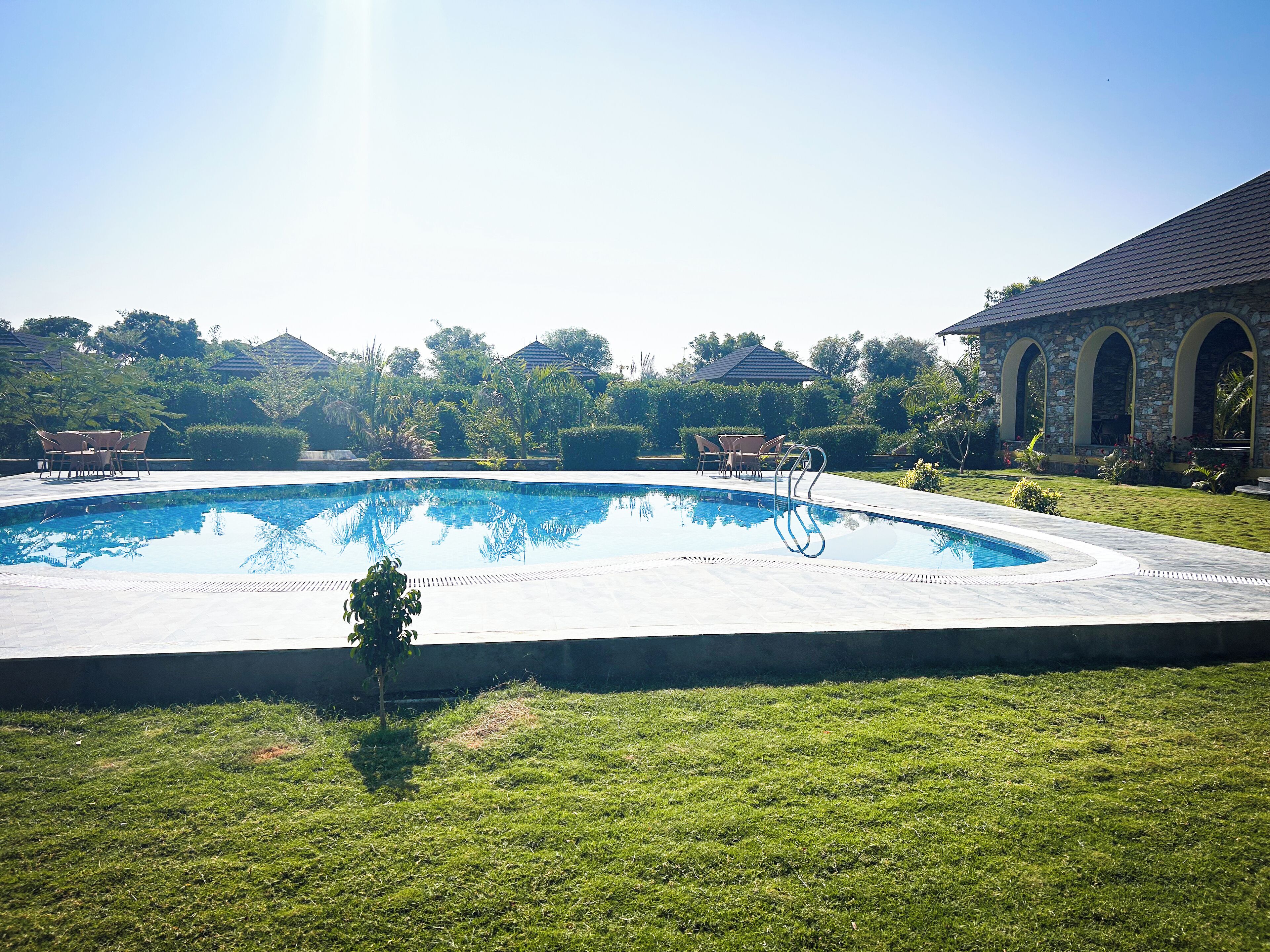 Piscina com um edifício de pedra ao fundo.