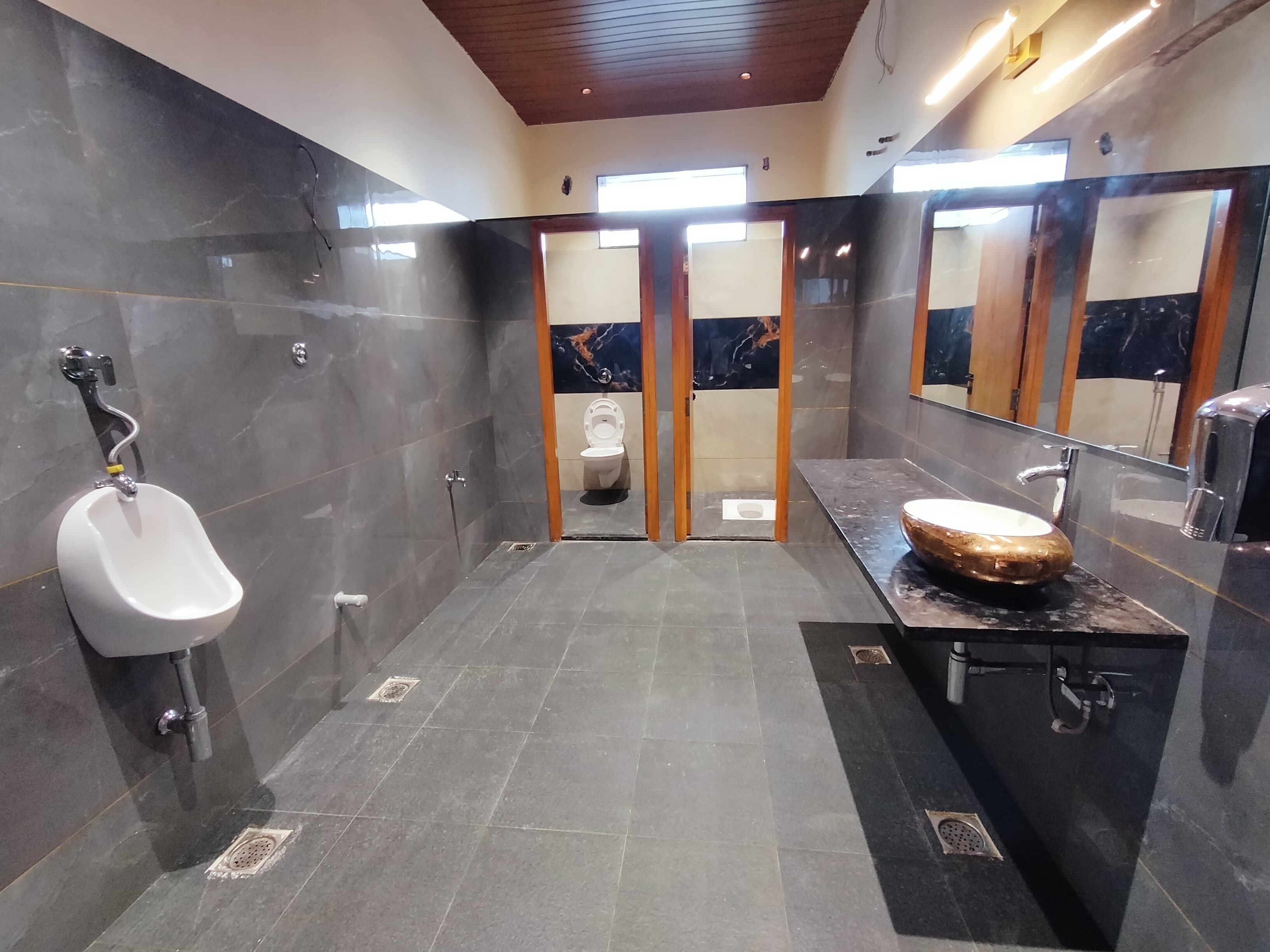 A modern bathroom with a urinal, a toilet, and a vanity with a large mirror.