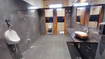 A modern bathroom with a urinal, a toilet, and a vanity with a large mirror.