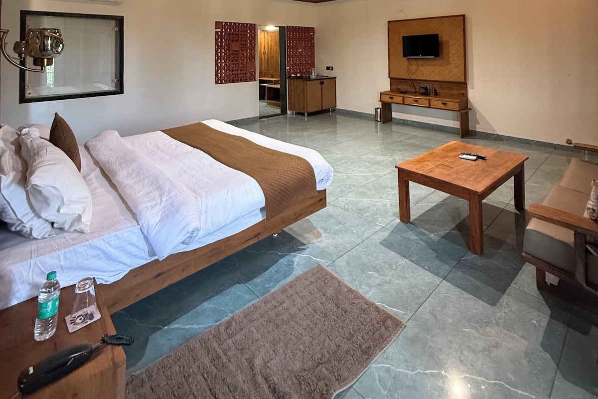 Une chambre dâhĂŽtel moderne dotĂ©e dâun grand lit, dâun tĂ©lĂ©viseur Ă Ă©cran plat, dâune table basse en bois et dâun ventilateur de plafond.
