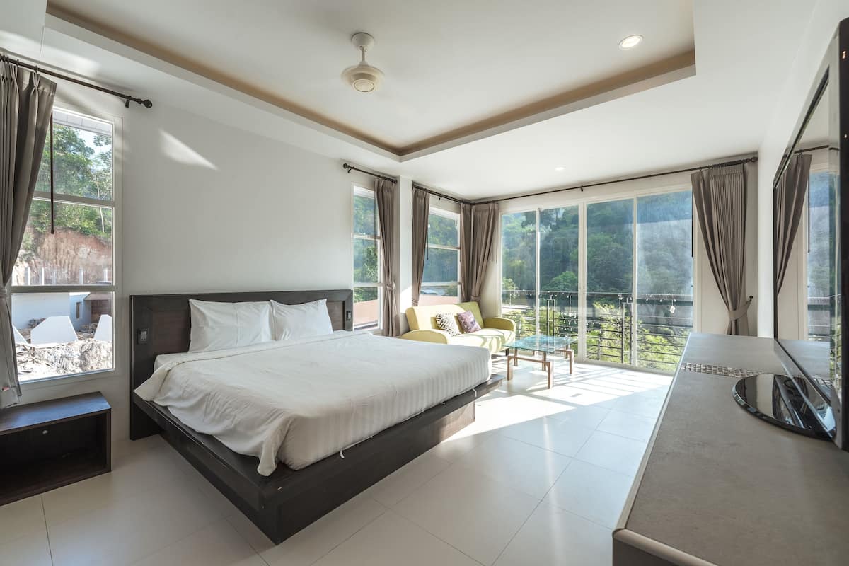 Een moderne hotelkamer met een groot bed, een sofa en een balkon met uitzicht.
