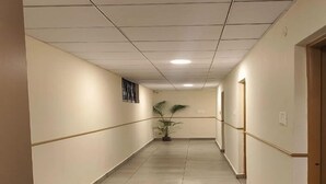 A long, narrow hallway with a tiled floor and a ceiling with recessed lighting. - Diya residence (Mysore)