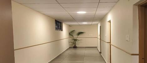 A long, narrow hallway with a tiled floor and a ceiling with recessed lighting.