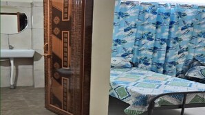A bedroom with a bed, a bathroom with a sink, and a door leading to another room. - Diya residence (Mysore)