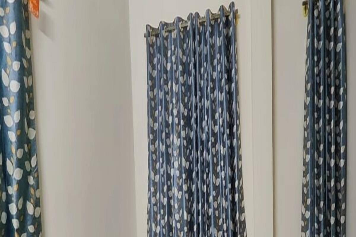 Une chambre avec un lit, une fenêtre avec des rideaux et une barrière de lit fixée au mur.