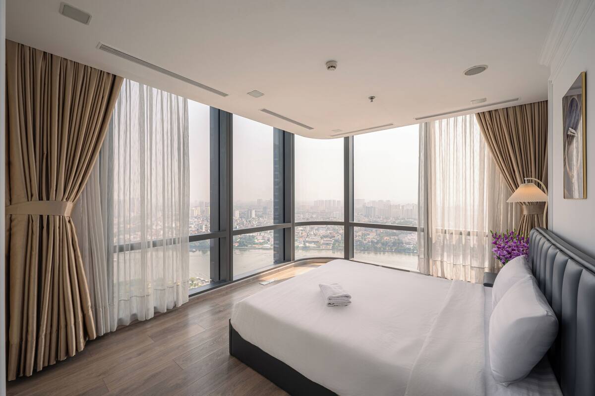 Une chambre d’hôtel moderne avec un grand lit, une vue sur la ville et un balcon.