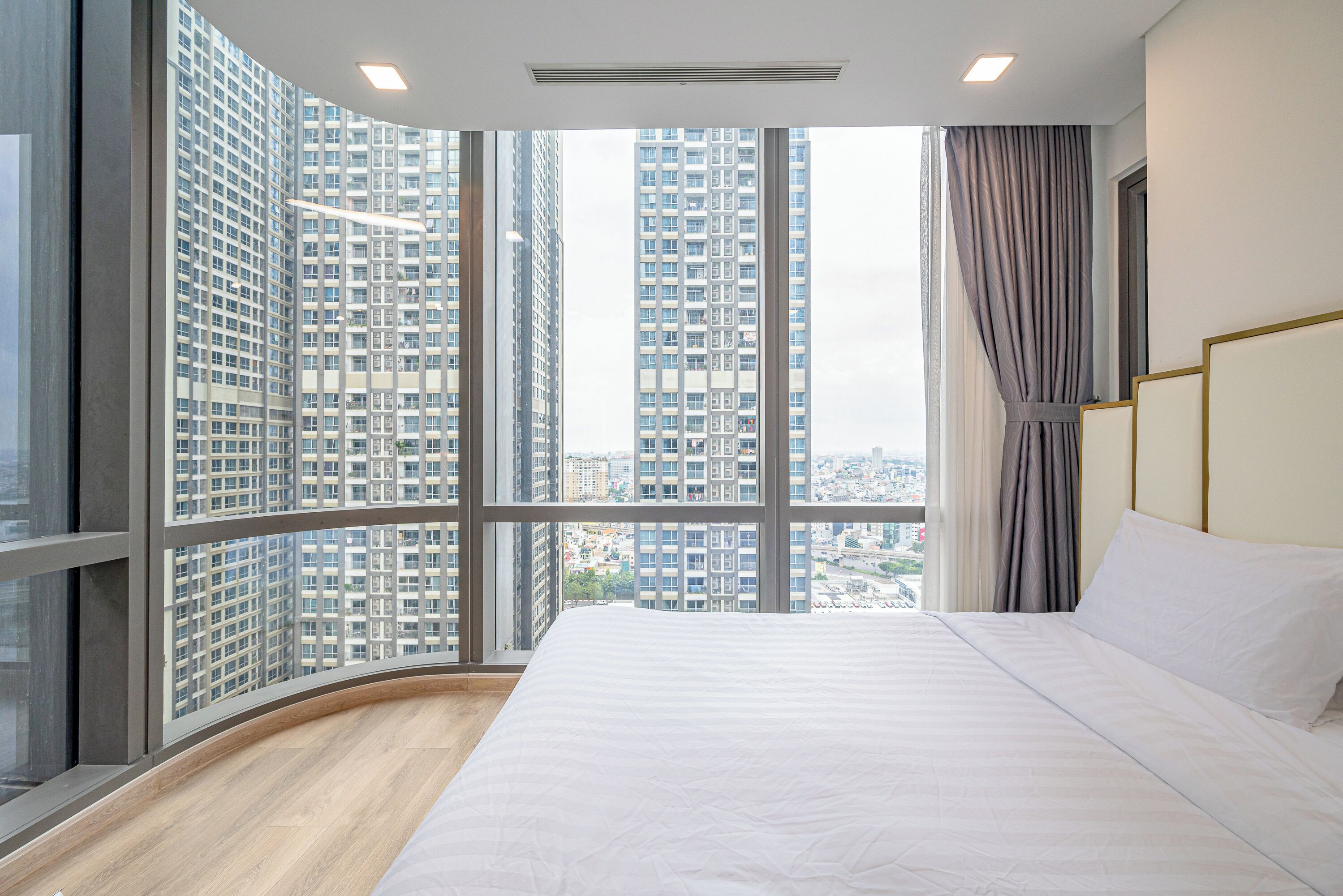 A hotel room with a large window, a bed, and a view of tall buildings.