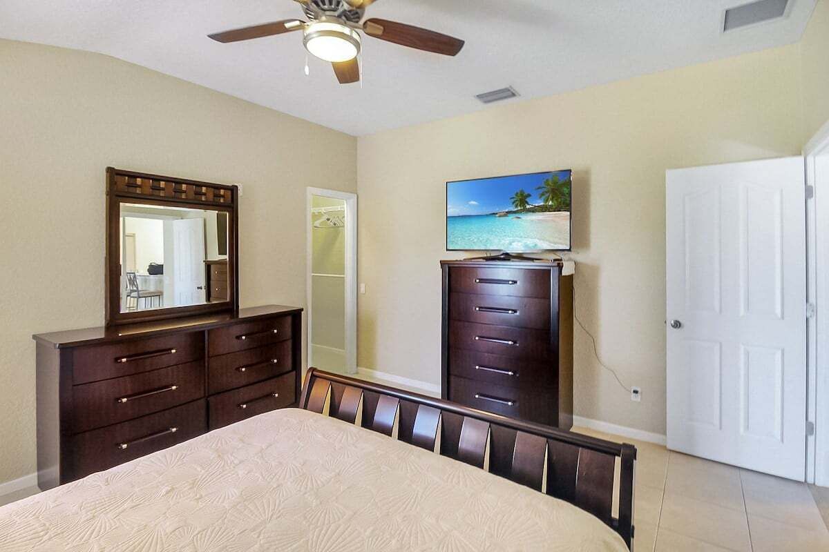 A bedroom with a bed, a dresser, a television, and a door.