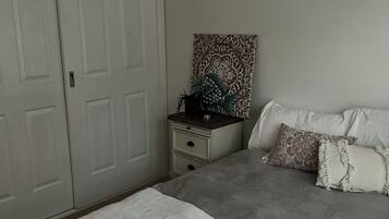Une chambre à coucher comprenant un lit, une table de chevet, un élément décoratif mural et une armoire.