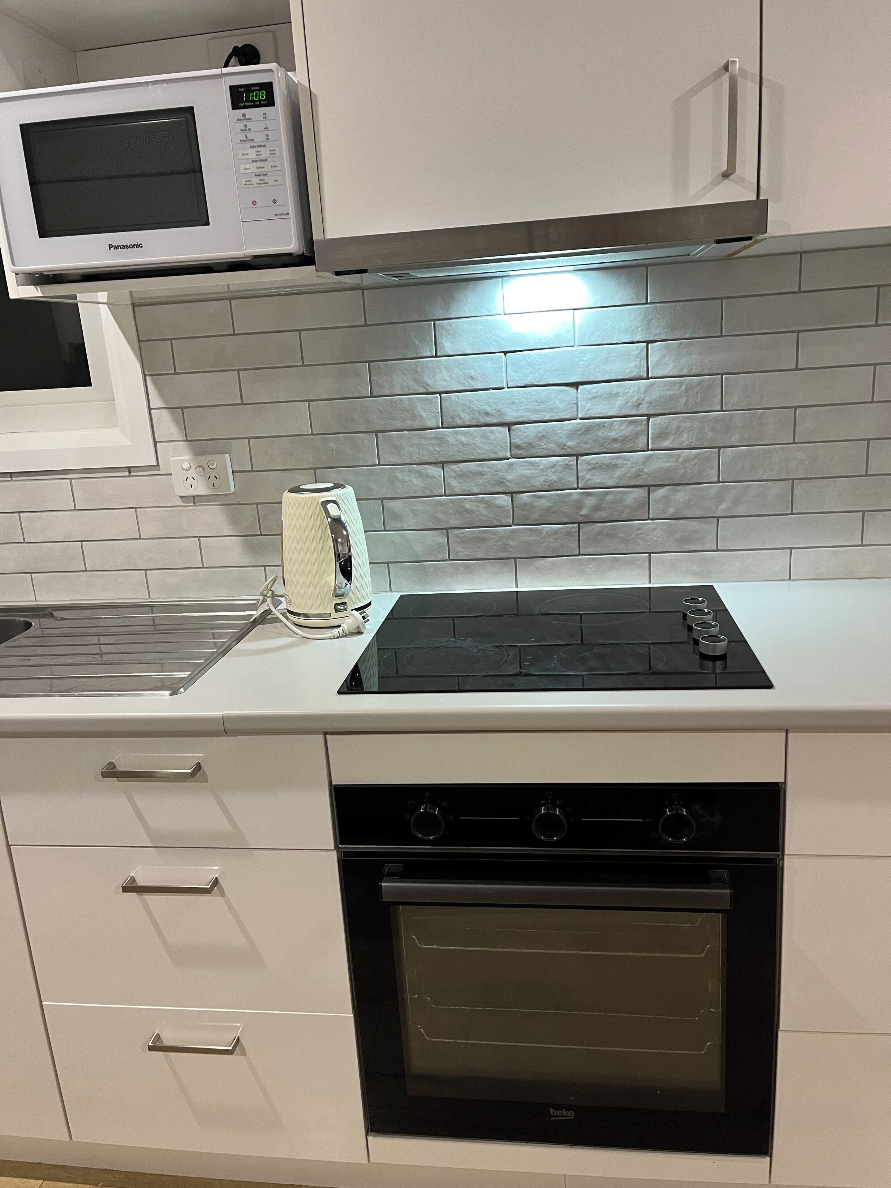 A kitchen with a microwave, toaster, stove, oven, and a tiled backsplash.