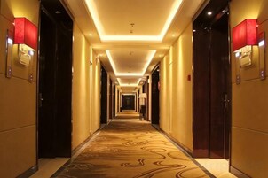 Un pasillo de hotel con piso alfombrado, puertas a ambos lados e iluminación en el techo.