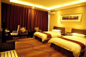 Ein Hotelzimmer mit zwei Betten, einem Schreibtisch, einem Stuhl und einem großen Fenster mit Vorhängen.