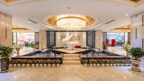 Een hotelhal met een statige kroonluchter, een piano en een centraal zithoek.
