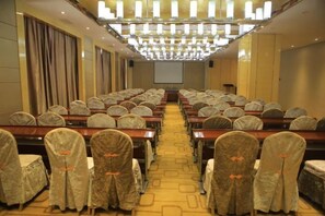 A conference room with rows of tables and chairs, a projector screen at the front, and a chandelier overhead. - Yuyang International Hotel (Gaotai)