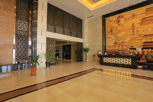 A spacious lobby with a polished floor, decorative screens, and a mural depicting traditional architecture.