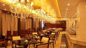 Een restaurantgedeelte in een hotel met meerdere tafels en stoelen, een bar en een grote kroonluchter.