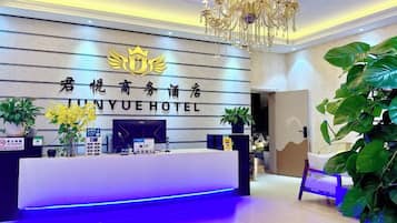 A reception desk with a chandelier, potted plants, and a sign for JINYUE HOTEL.