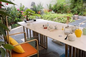 A dining table with chairs, a tea set, and a potted plant.