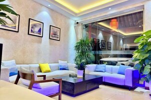 Uma sala de estar moderna com sofá, mesa de centro e poltronas, uma planta grande e obras de arte nas paredes.