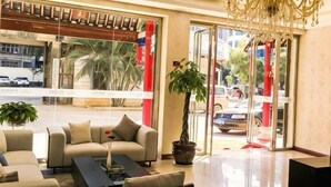 Eine Lobby mit einer Couch, einem Couchtisch, einer Chandelüster, einem Blumentopf und Glastüren zum Außenbereich.