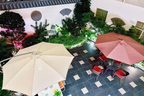 A terrace with two umbrellas, a tiled floor, and indoor plants.