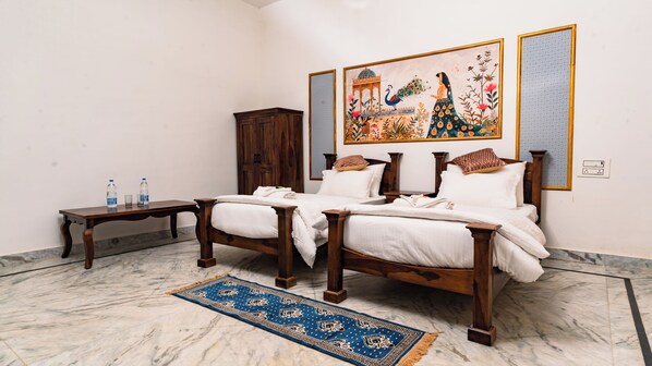 A hotel room with a wooden bed, a marble floor, a blue patterned rug, a wooden cabinet, and a wall with a colorful painting.