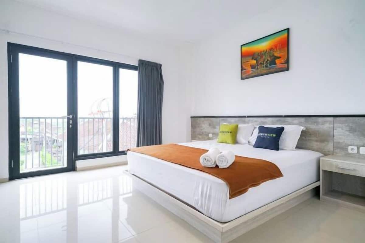 Une chambre d’hôtel avec un grand lit, un tableau au mur et un balcon avec vue.
